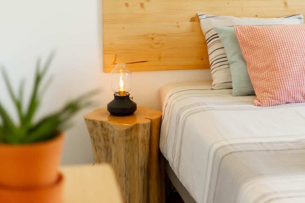 Detail of a bedroom with bedside table, bed light and plants